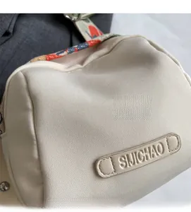 Detail of canvas shoulder bag showing textile texture and leather logo tag with strap