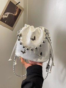 White croc-effect drawstring bucket bag with silver butterfly charms and beaded handle