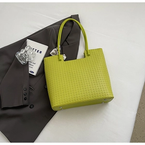 Détail du cabas tressé vert tilleul avec clous de protection et foulard en soie imprimé