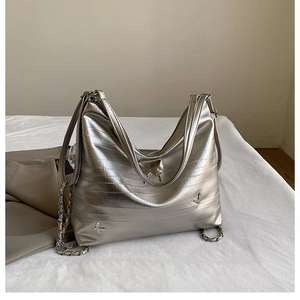 Dettaglio borsa hobo argento con texture orizzontale e decoro a farfalla in metallo