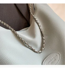 Detail of light green lychee leather texture and woven chain strap on fashion bag