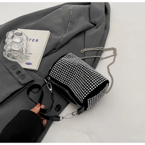 Detail of black rhinestone cylinder bag with silver chain and leather strap on suit