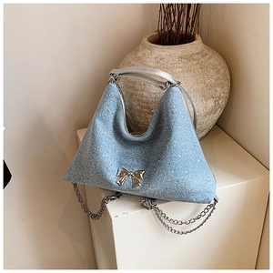Dettaglio della borsa tote in tweed azzurro con fiocco argento e tracolla a catenella
