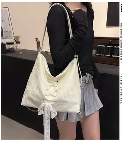 Detail of cream tote bag featuring marble texture, lace bow and metal chain strap