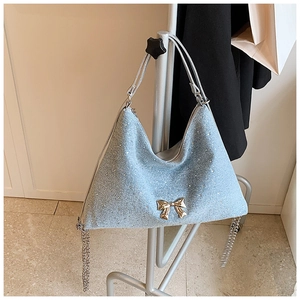 Dettaglio della borsa tote azzurra con fiocco, paillettes argentate e catena a nappa
