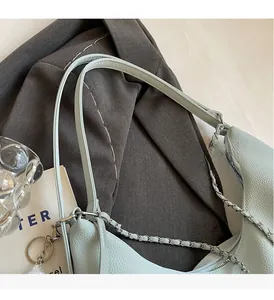 Macro detail of mint green litchi texture leather bag with silver chain and leather strap