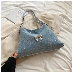 Dettaglio della borsa tote in denim blu con strass argento e fiocco metallico