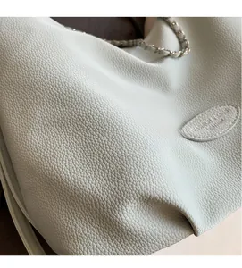 Close-up of light blue lychee pattern leather texture with woven chain strap detail