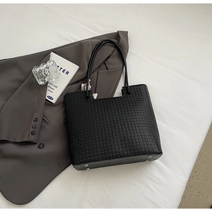 Détail du fond d'un cabas noir tressé avec quatre rivets de protection en métal au sol