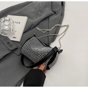 Detail of silver rhinestone cylinder clutch bag with chain strap on grey blazer