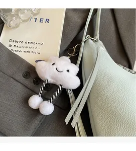 Close-up of a cute white plush cloud charm with a smiley face on a blue leather bag