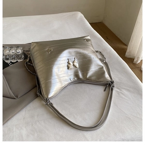 Dettaglio borsa argento metallizzato con farfalla 3D e tracolla a catena lucida elegante