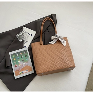 Détail du grand sac cabas tressé marron avec foulard en soie et rivets de base