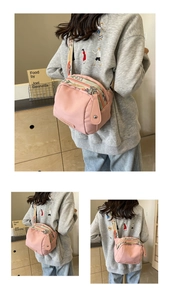 Detail of pink nylon crossbody bag featuring bohemian floral embroidery strap and leather pulls