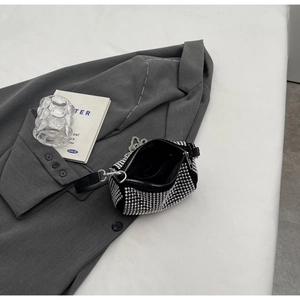 Close-up of a sparkling black rhinestone mini handbag on a grey blazer with silver chain