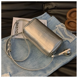 Detail of silver metallic pillow bag with textured finish and decorative chrome sphere charm