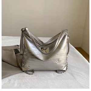 Dettaglio della borsa tote argento metallizzato con decori a farfalla e tracolla a catena