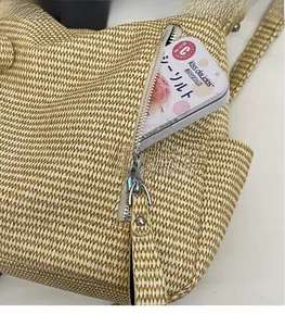 Detail of woven straw tote bag featuring a front zipper pocket with functional storage