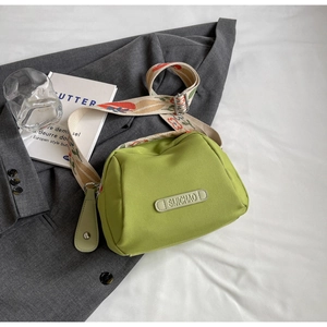 Detail of avocado green crossbody bag with colorful embroidered wide strap and rubber label