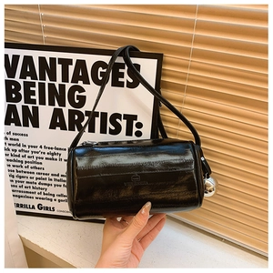 Close-up of black glossy cylindrical Boston bag featuring zipper closure and leather texture