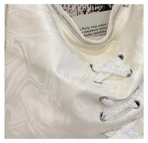 Detail of marble pattern fabric with lace ribbons and silver zippers on a white bag