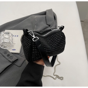 Detail of black rhinestone cylinder bag with silver metal chain and leather strap