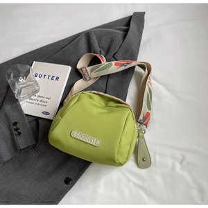 Detail of avocado green shell bag featuring a wide floral print strap and brand logo