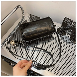Close-up of black cylindrical pillow bag with silver metal ball and glossy texture