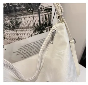 Detail showing smooth silver metal zipper and textured white PU leather on the tote bag
