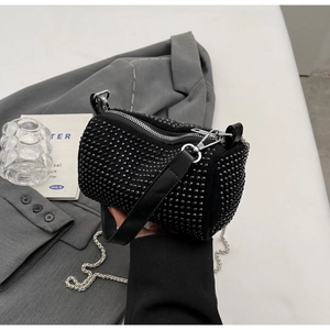 Detailed macro shot of black rhinestone cylinder bag with silver zipper and dual straps