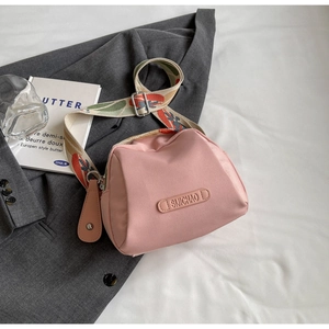 Detail of pink canvas crossbody bag with decorative wide jacquard strap and brand logo