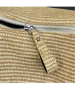 Detailed close-up of woven straw texture and premium silver metal zipper puller on tote bag