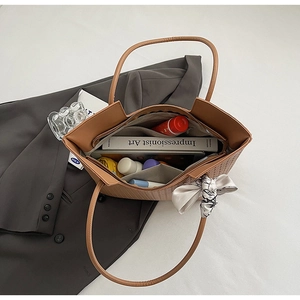 Intérieur spacieux du sac cabas tressé contenant livre, parapluie et cosmétiques