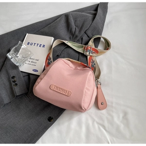 Macro detail of pink canvas crossbody bag featuring vintage floral jacquard strap and logo