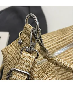 Detail of silver lobster clasp and D-ring on a beige woven tote bag with straw texture
