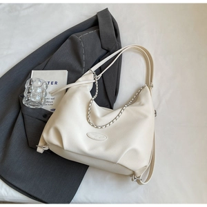 Detail of creamy white dumpling bag with pebbled leather texture and silver chain
