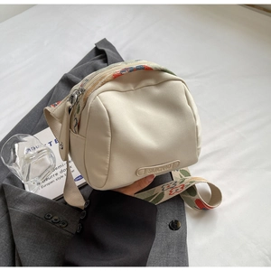 Detail of cream nylon crossbody bag featuring vibrant floral jacquard wide shoulder strap