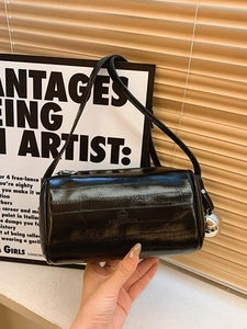 Minimalist black pillow cylinder bag with glossy crinkle texture and silver shoulder strap