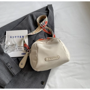 Detail of off-white canvas shell bag featuring a wide jacquard strap and brand logo
