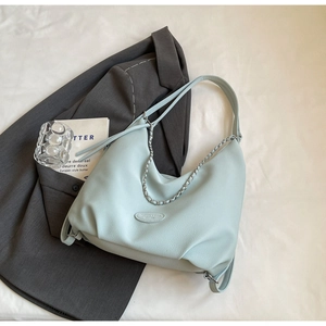 Detail of mint green hobo bag with pebble leather texture and silver chain decoration