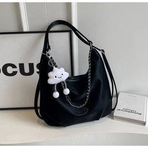 Detail of black matte leather hobo bag with silver chain and white fluffy charm