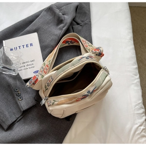 Detail view of cream oxford shell bag featuring a colorful jacquard wide shoulder strap