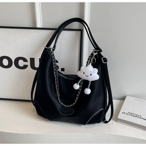 Detail of black lychee grain tote bag with silver chain and white plush cloud charm