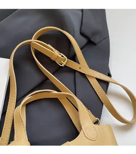 Close-up of adjustable strap with gold buckle on lychee textured beige bucket bag