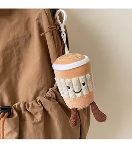 Detail of coffee cup plush charm with smile embroidery hanging on a brown backpack