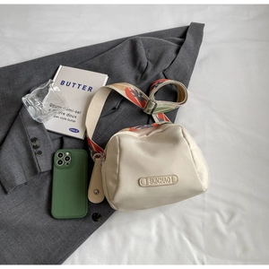 Detail of canvas shell bag with a colorful jacquard strap and brand leather tag