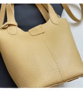 Macro detail of ginger yellow pebbled leather bucket bag with premium vertical stitching