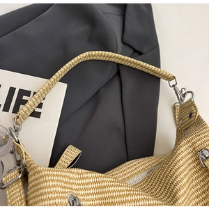 Close-up of beige woven texture and silver metal D-ring buckle on a shoulder tote bag