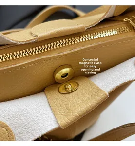 Detailed close-up of yellow leather bag featuring a secure magnetic snap and gold zipper