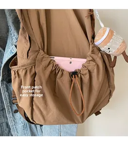 Front pleated pocket of khaki nylon backpack holding a tablet for storage detail